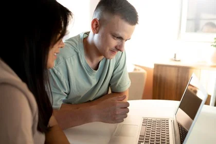 A man and woman looking at a laptop together at a table