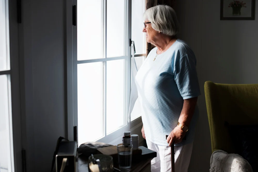 Elderly woman in home looking out window Elderly woman in home looking out window