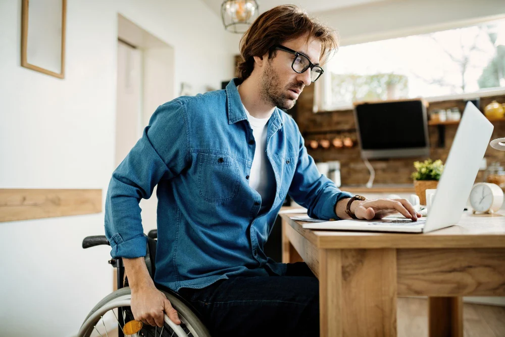 Man in wheelchair looking at laptop Man in wheelchair looking at laptop