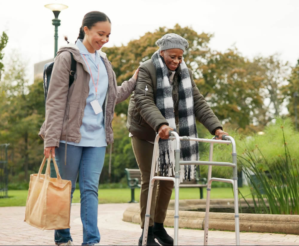 Assistant support woman using walker in park Social and Community Participation