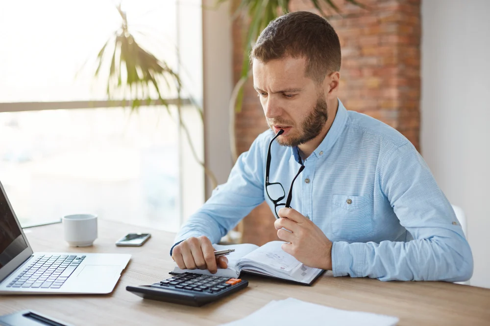 Man checking NDIS service agreement costs with a calculator Man checking NDIS service agreement costs with a calculator
