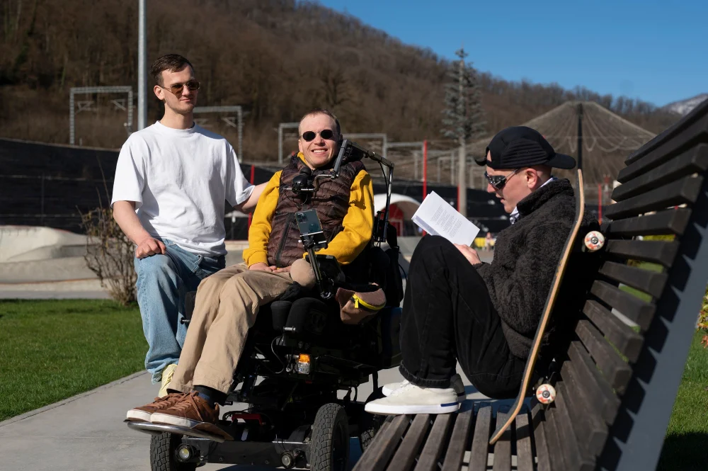 Man using a powered wheelchair enjoying a community outing with two companions