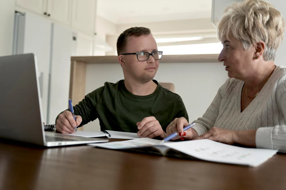 Man with Down syndrome reviewing NDIS service agreement with support person Man with Down syndrome reviewing NDIS service agreement with support person