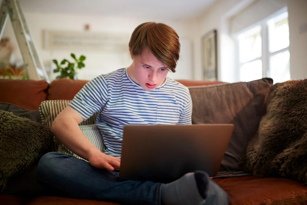 NDIS Replacement Supports and Technology NDIS participant using a laptop at home as an example of technology that may be considered a replacement support
