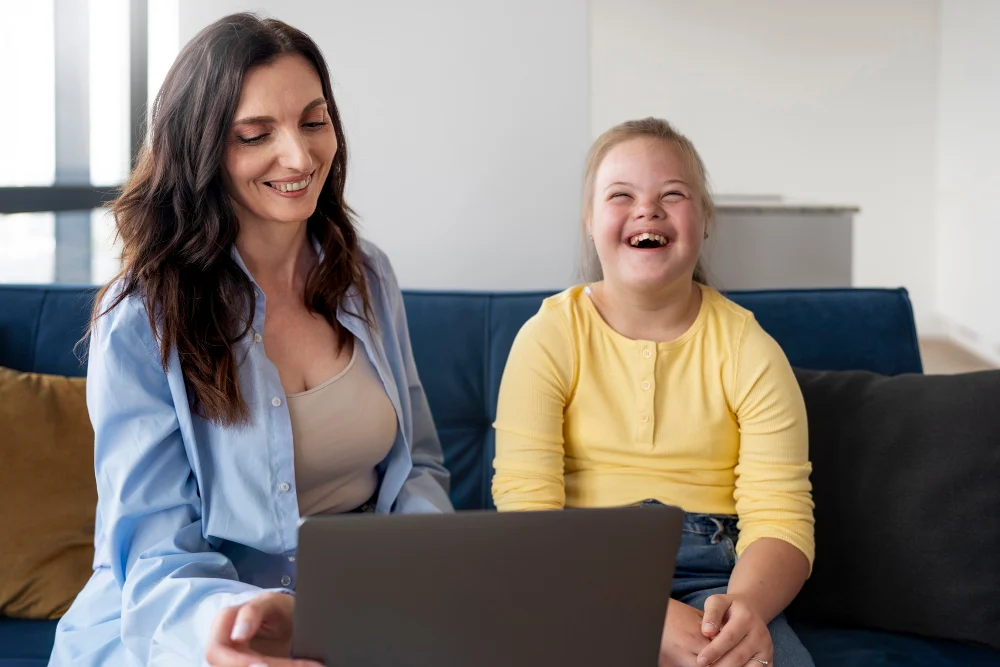 NDIS Skill Building Support at Home Support worker helping a young NDIS participant use a laptop at home