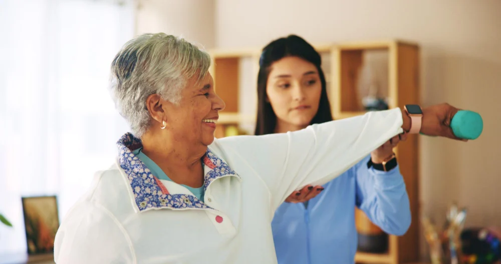 NDIS Therapy Support at Home Therapist supporting an older NDIS participant with arm exercises at home