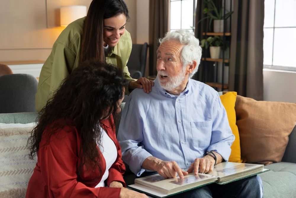 Older man sharing a photo album with two women at home
