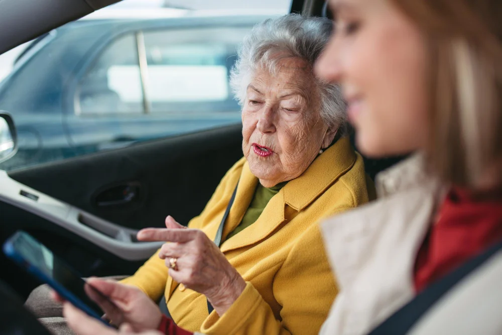 Older woman and support worker checking transport details in a car