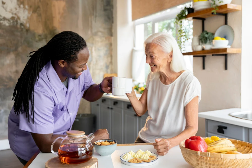 Support worker sharing tea with an older woman in a home kitchen