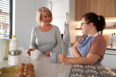 two women talking in home kitchen baking ingredients