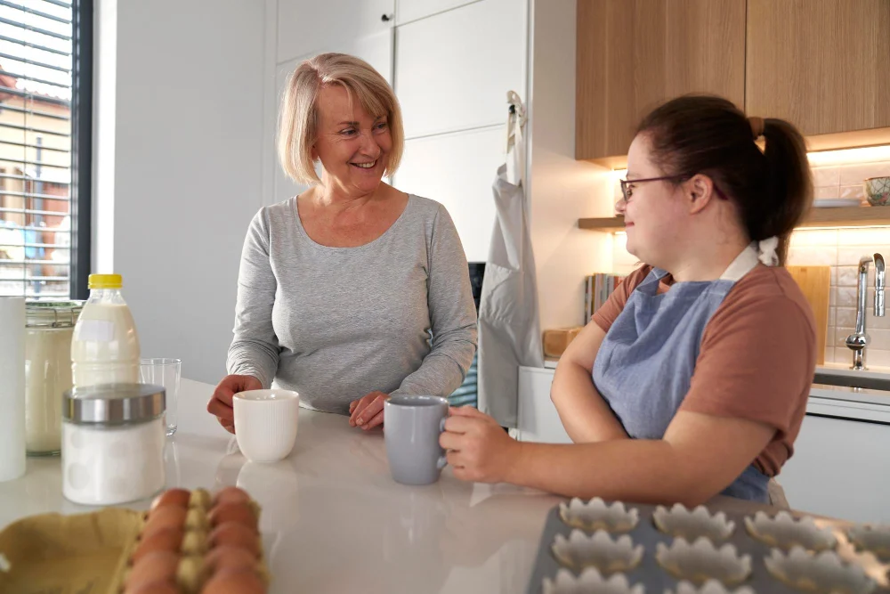 Two women talking together in a home kitchen with baking ingredients on the counter Two women talking together in a home kitchen with baking ingredients on the counter