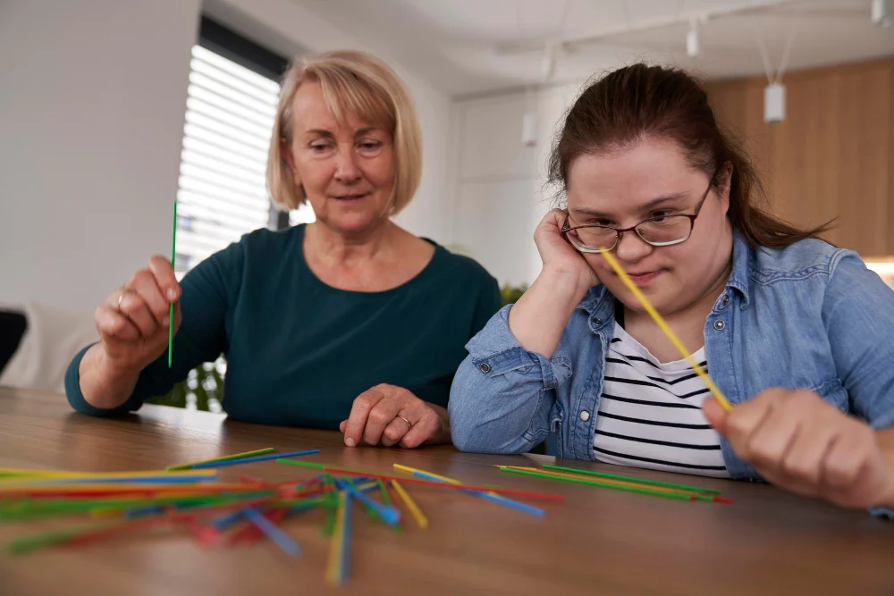 Woman completing an activity with support from another woman at home Woman completing an activity with support from another woman at home
