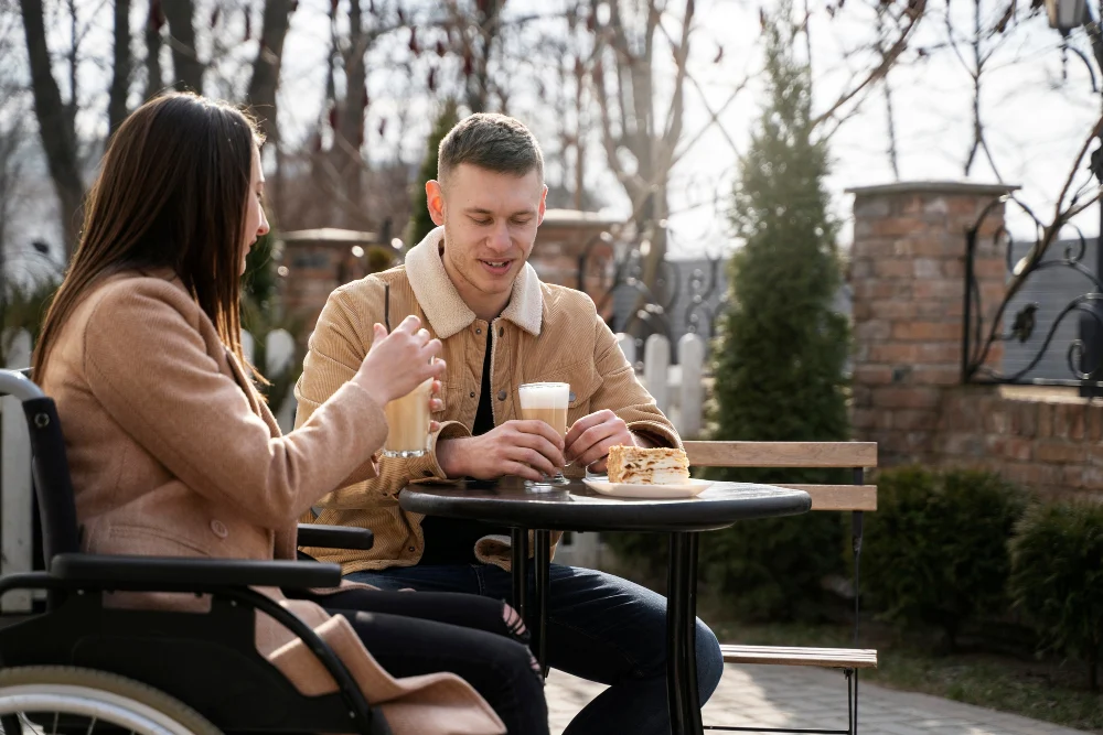 Woman using a wheelchair enjoying a community outing at an outdoor café with a companion